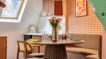 A dining area with a round table, chairs, a vase with flowers, and a checkered wall.