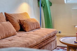 A sofa with multiple cushions, a round side table, and a green vertical object in the background. - New Listing (Rouen)