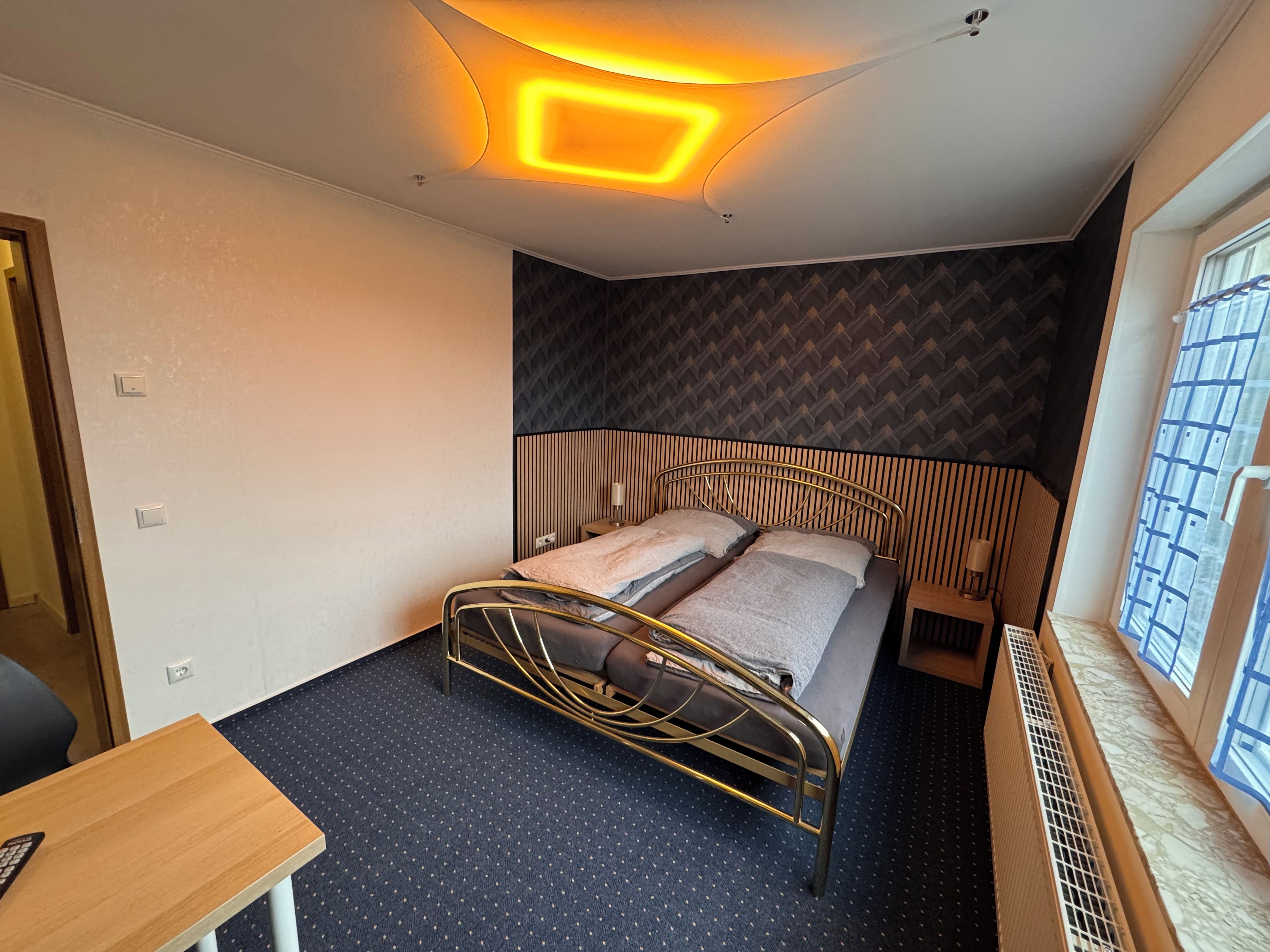 Een kleine kamer met een enkel bed, een bureau en een raam.