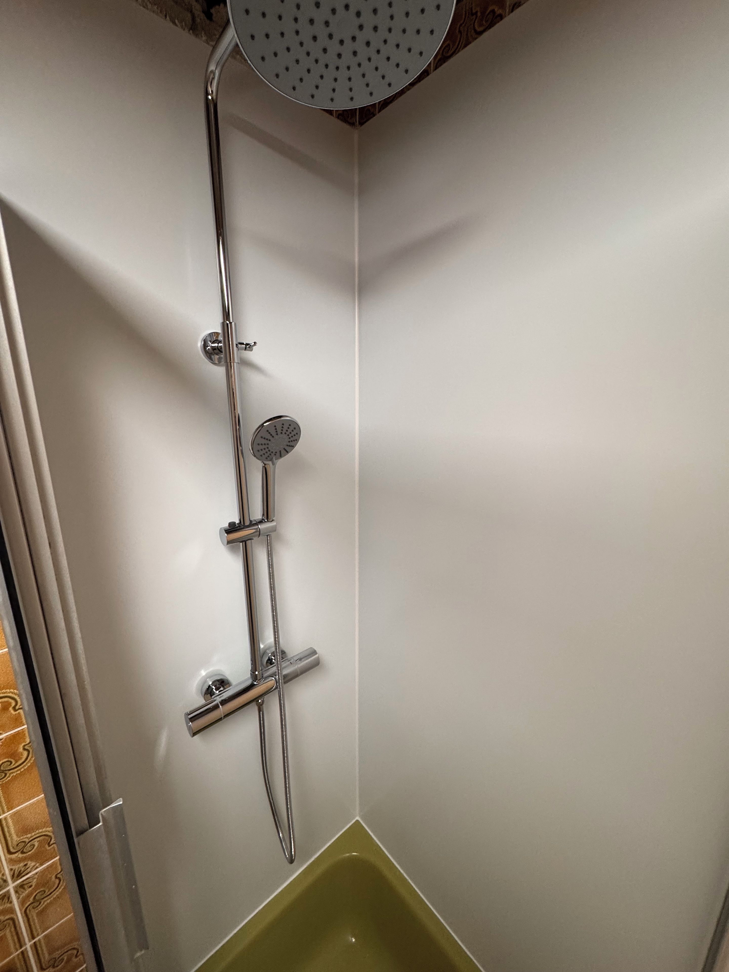 Eine Eckdusche mit Handbrause und Reinigungsbürste.