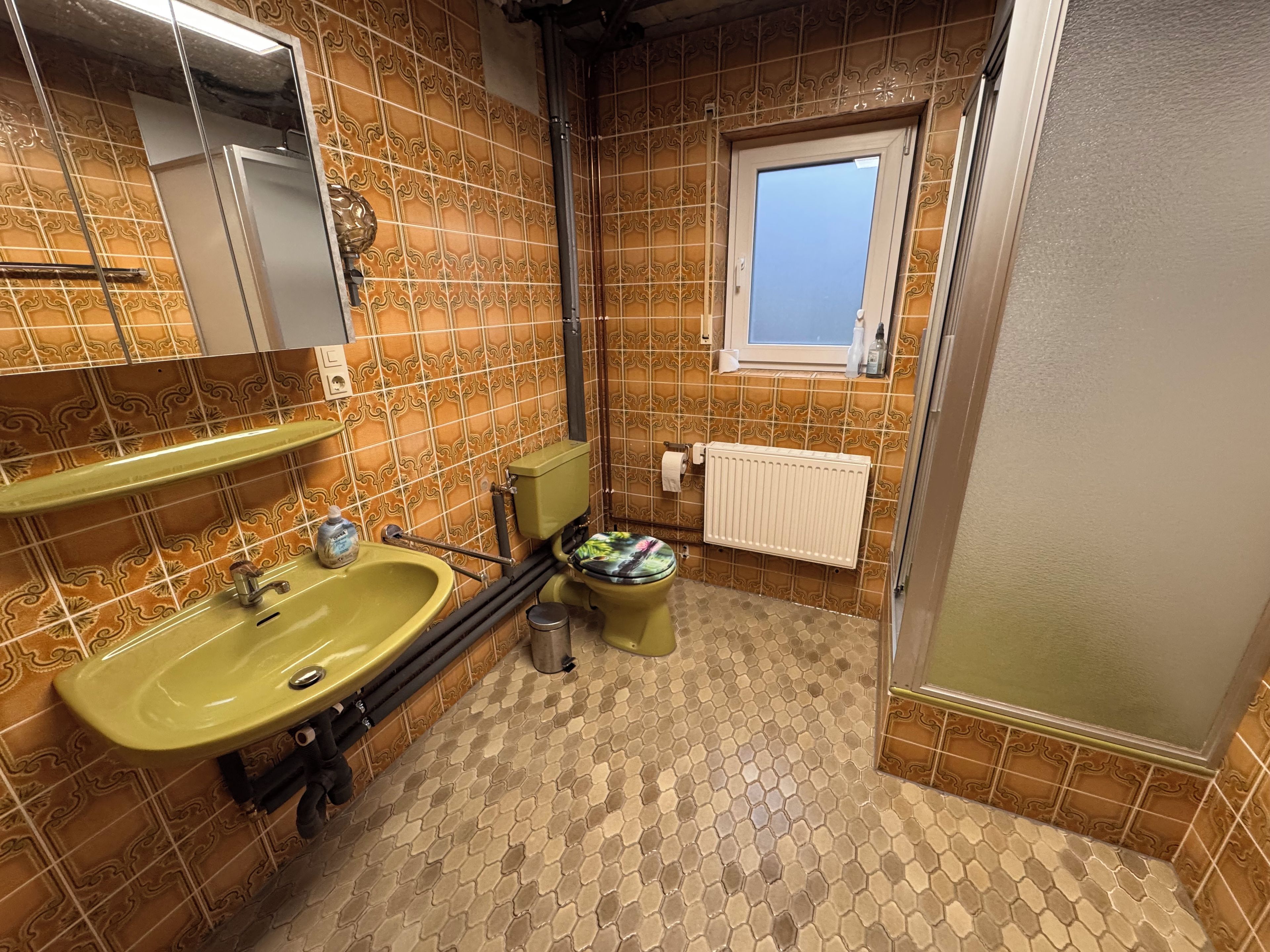 Ein Badezimmer mit einem grünen Waschbecken, einer Toilette und einem Fenster.