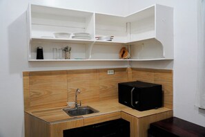 Een kleine keuken met een spoelbak, een magnetron en bovenkasten voor opbergruimte.