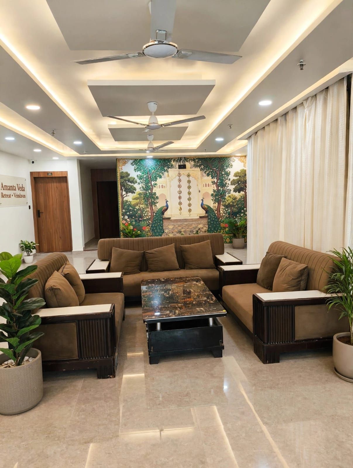 A modern living room with a sofa set, a coffee table, and a mural of peacocks.