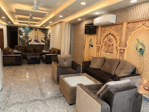 A modern living room with a sofa set, a coffee table, and a decorative wall with cultural artwork. - AMANTA VEDA powered by Conara Connect (Varindavan)