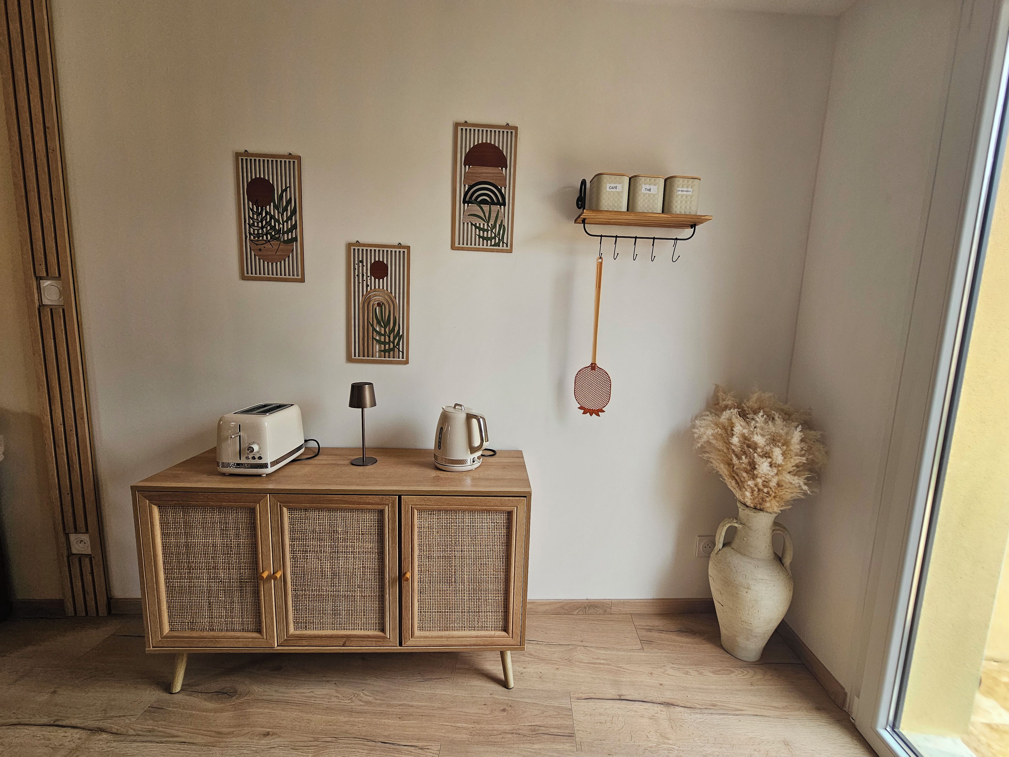 Ein Zimmer mit einem Holzkasten, einem Wasserkocher, einer Lampe und Wanddekorationen.