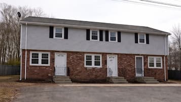 A two-story residential building with a brick facade, white trim, and a flat roof.