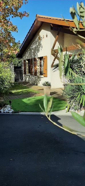 Une maison avec un toit en pente, un porche à l’avant et une pelouse bien entretenue.