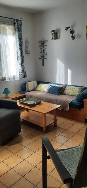 Un salon comprenant un canapé, une table basse, un fauteuil et une petite table avec une lampe.