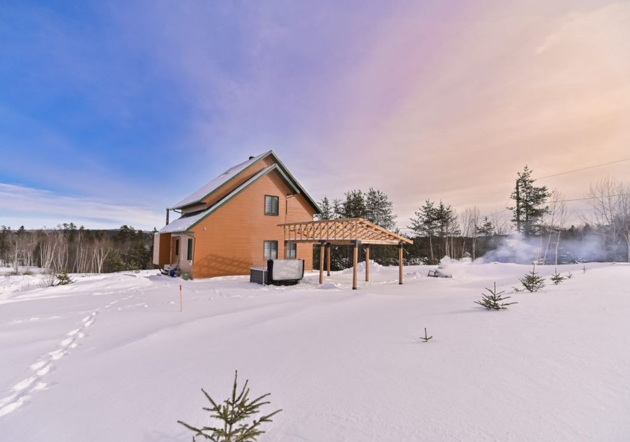 A house with a wooden exterior, a covered patio, and a snow-covered yard.