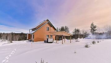 A house with a wooden exterior, a covered patio, and a snow-covered yard.