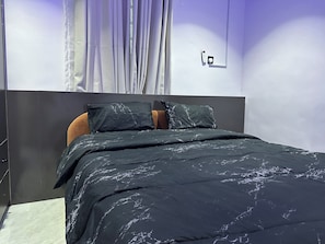 A bedroom with a bed, curtains, a wall-mounted phone, and a door. - Elara Unit—Secure, Stylish 1-bed in Lagos — 24/7 power AC, Wi-Fi & full kitchen (Lagos)