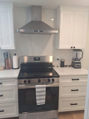 A kitchen with a stainless steel stove, a range hood, and a blender on the countertop. - Siesta Key 2-bedroom house -Walk to #1 Siesta Key Beach, Sun & Fun (Sarasota)