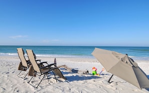 Une plage avec deux chaises longues et un parasol sur le sable.
