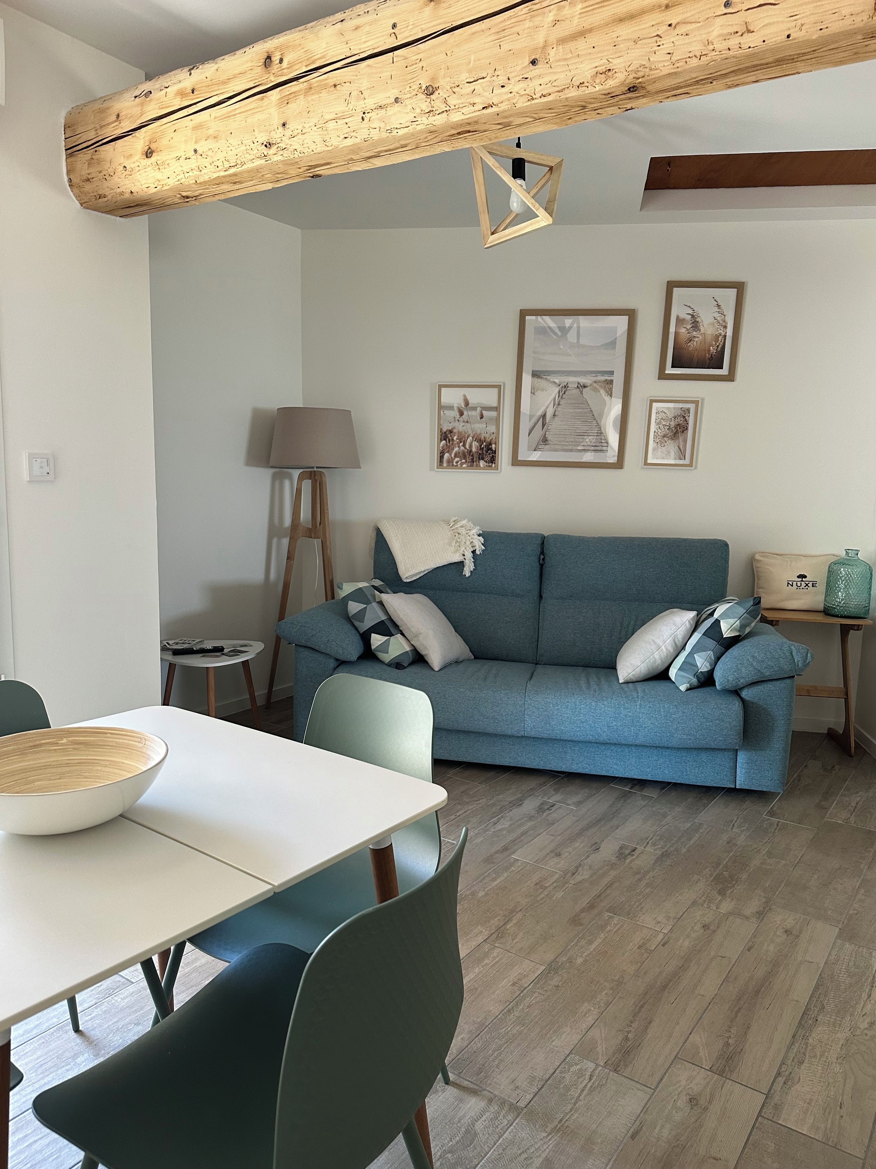 A modern living room with a blue sofa, a dining table, and a lamp.
