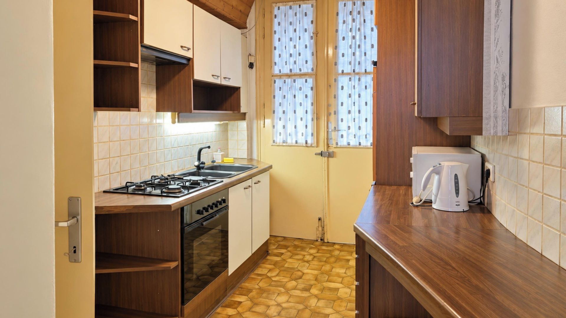 Een kleine keuken met een gasfornuis, oven en een koffiezetapparaat op het aanrecht.