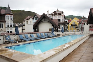 Piscina com espreguiçadeiras e vista para edifícios coloridos.