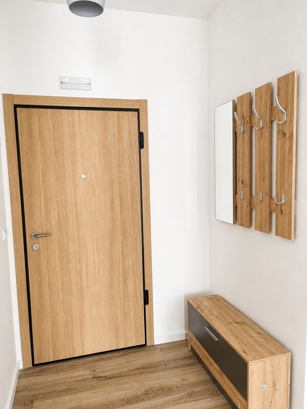 Uma porta de madeira com moldura preta, um pequeno banco e um cabideiro fixado na parede.
