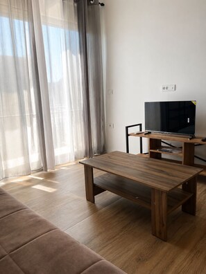 Uma sala de estar com uma mesa de centro de madeira, um sofá e uma TV em um móvel.