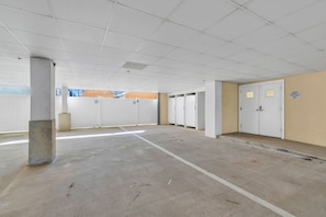 A parking garage with concrete floors and white walls, featuring multiple parking bays and a central walkway. - 4 Bedroom Rooftop Retreat in beautiful Seaside Heights (Seaside Heights)