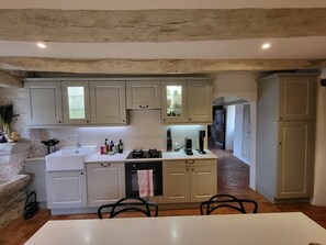 A kitchen with a central island, white cabinets, and a stone accent wall. - New Listing (Caylus)
