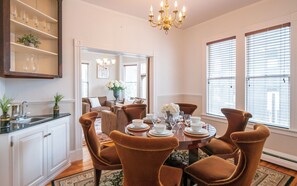 Ein Esszimmer mit einem runden Tisch, gedeckt für sechs Personen, umgeben von sechs braunen Polsterstühlen.