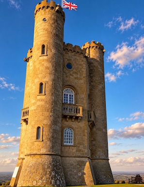 A historic stone tower with a flag, windows, and a balcony.