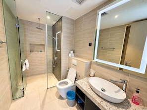 Une salle de bain moderne avec une douche à parois de verre, des toilettes blanches et un grand miroir.
