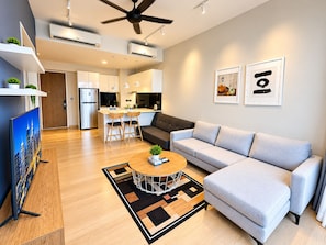 A modern living room with a grey sofa, a coffee table, and a TV. - Star KLCC by Alpha Home-Stay (Kuala Lumpur)