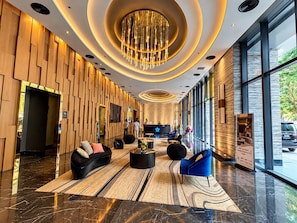 Een moderne hotellobby met een centraal zitgedeelte, een receptiebalie en grote ramen.