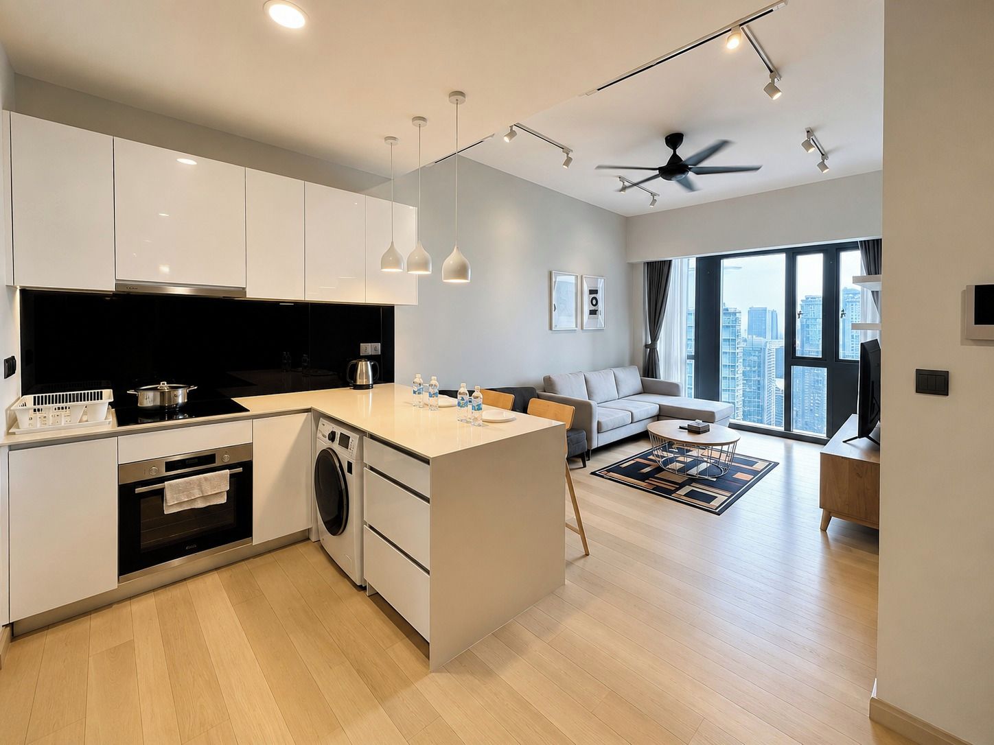A modern kitchen with built-in appliances, a dining area with a round table, and a living space with a sofa and large windows.