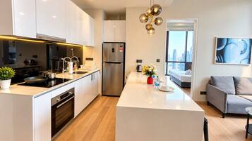 A modern kitchen with a central island, stainless steel appliances, and a view to the living area.
