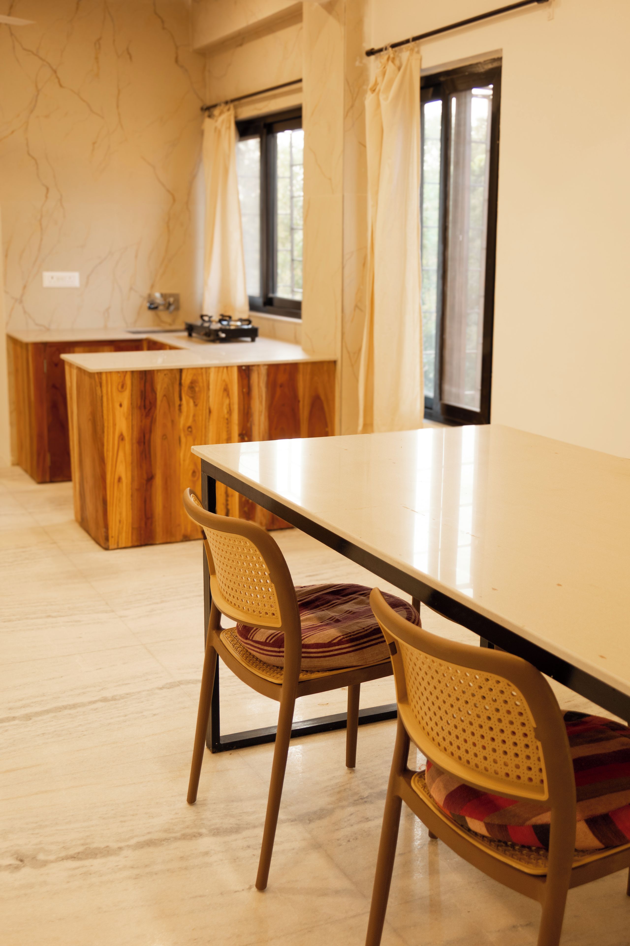 Una cocina moderna con una isla de madera, una mesa de comedor con sillas y vistas al exterior a través de grandes ventanales.