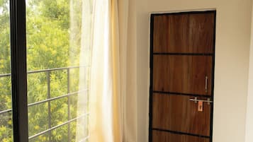 Une pièce avec un banc en bois près d’une fenêtre, une porte et un appareil de climatisation.