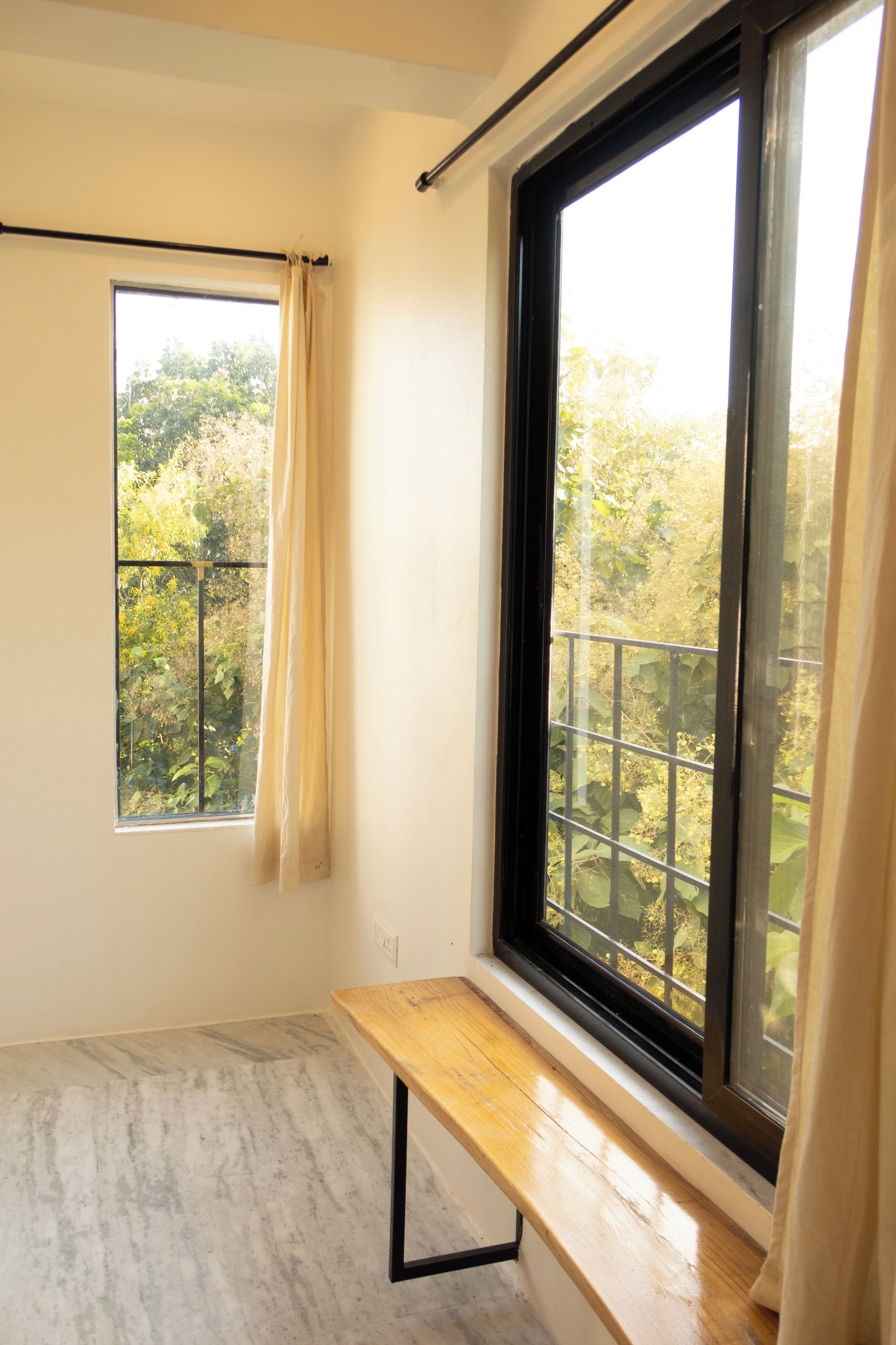 Una habitación con un ventanal grande, un banco de madera y una cortina.