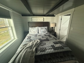Une chambre à coucher avec un lit, une lampe de chevet, une fenêtre et une porte.