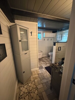 Une petite salle de bain comprenant des toilettes, un lavabo et un meuble avec une porte en verre.