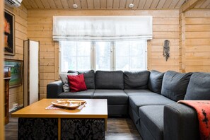 A cozy room with a sectional sofa, a wooden table, and a window with a white valance.