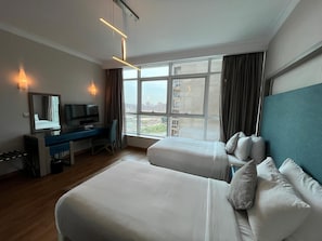 Ett hotellrum med två sängar, ett skrivbord, en TV och stora fönster.