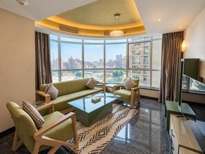Ein modernes Wohnzimmer mit einer Sofagarnitur, einem Couchtisch und Blick auf die Stadt durch große Fenster.