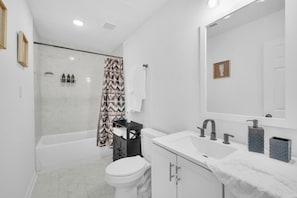 Une salle de bain moderne équipée d’une baignoire, de toilettes et d’un meuble-lavabo.