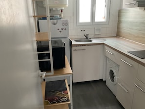 A compact kitchen with a built-in washing machine, a sink, and a window providing natural light. - New Listing (Notre-Dame-de-Monts)