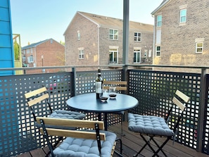 A balcony with a round table, two cushioned chairs, and a bottle of wine. - Walkable downtown Dayton MCM townhome with garage and balcony! (Dayton)