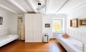 Ein Schlafzimmer mit zwei Betten, einem Kleiderschrank, einem Heizkörper und einem Fenster mit Blick.