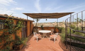 Eine Dachterrasse mit Tisch und Stühlen, einer Pergola und Blick auf die Stadt.