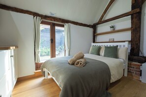 Un dormitorio con cama, ventana y vigas de madera.