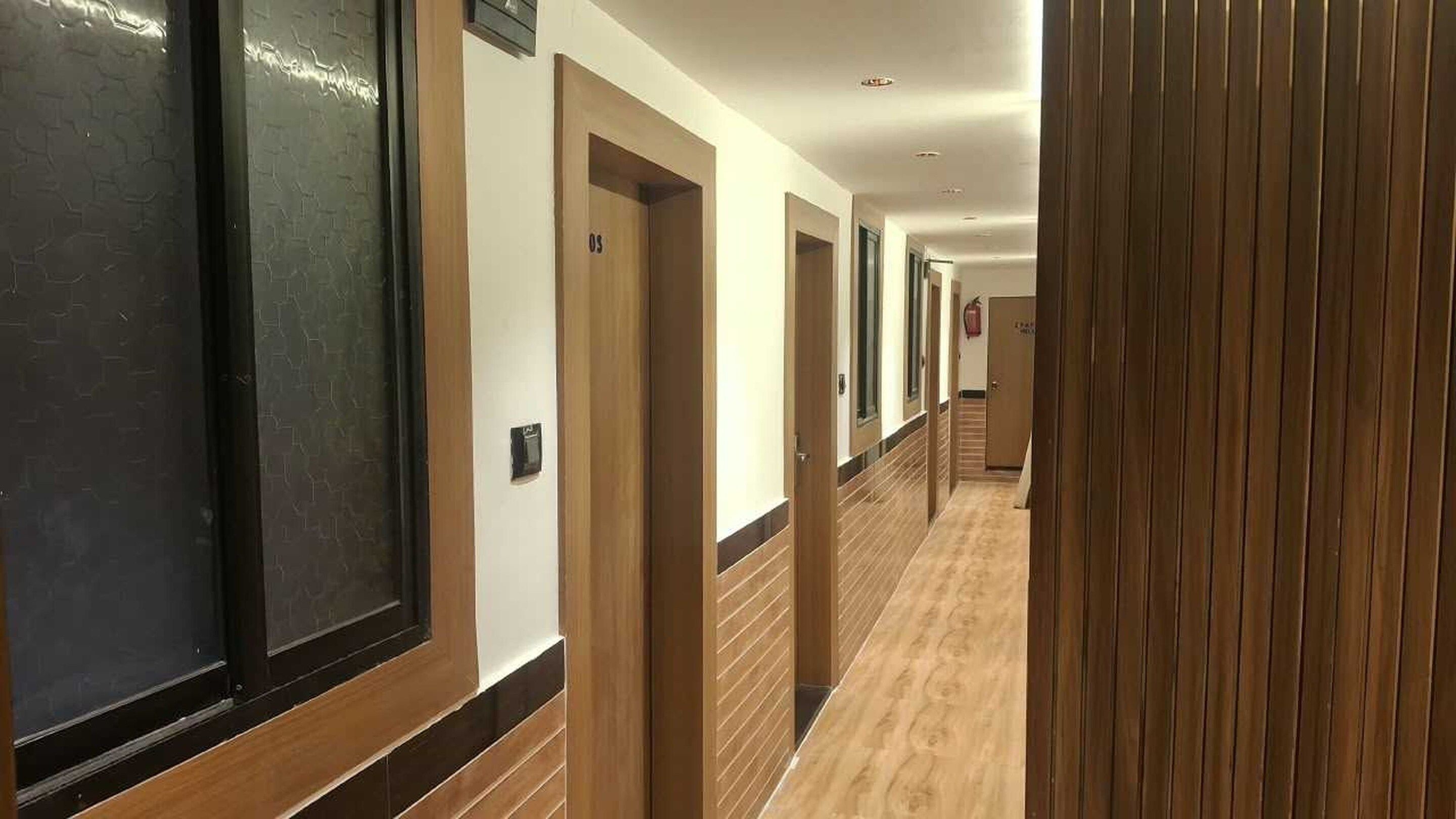A hotel corridor with wooden paneling, doors numbered 05, and a light-colored floor.