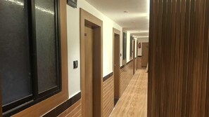 A hotel corridor with wooden paneling, doors numbered 05, and a light-colored floor. - Classic Hotel Blue Stone (Mumbai)