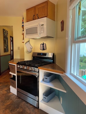 Une cuisine équipée d’une cuisinière, d’un four, d’un four à micro-ondes et de meubles de rangement en bois.