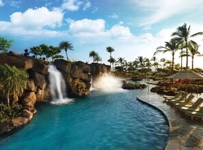 A resort pool with a waterfall, palm trees, and lounge chairs. - Hilton Grand Vacation Bay Club-Waikoloa - VILLA - XMAS - Dec 19 to Dec 26 2026 (Waikoloa Village)