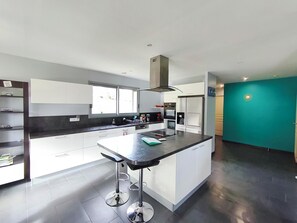 Een moderne keuken met een centraal eiland, roestvrijstalen apparatuur en een wand in turquoise.